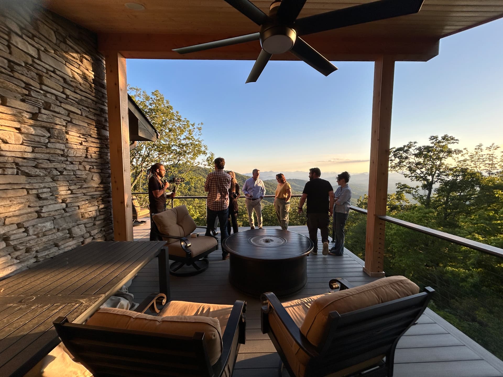 Film crew shooting on the terrace of a mountain home at sunset